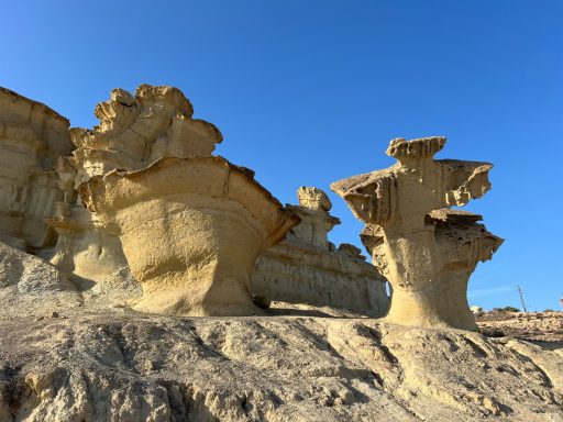 Geologische formaties met unieke, sculpturale rotsstructuren tegen een blauwe lucht.